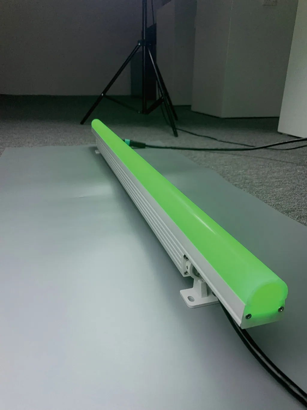 Long bar lit green on the studio floor; the catalogue caption reads "acrylic lampshade illuminated without dark areas".
