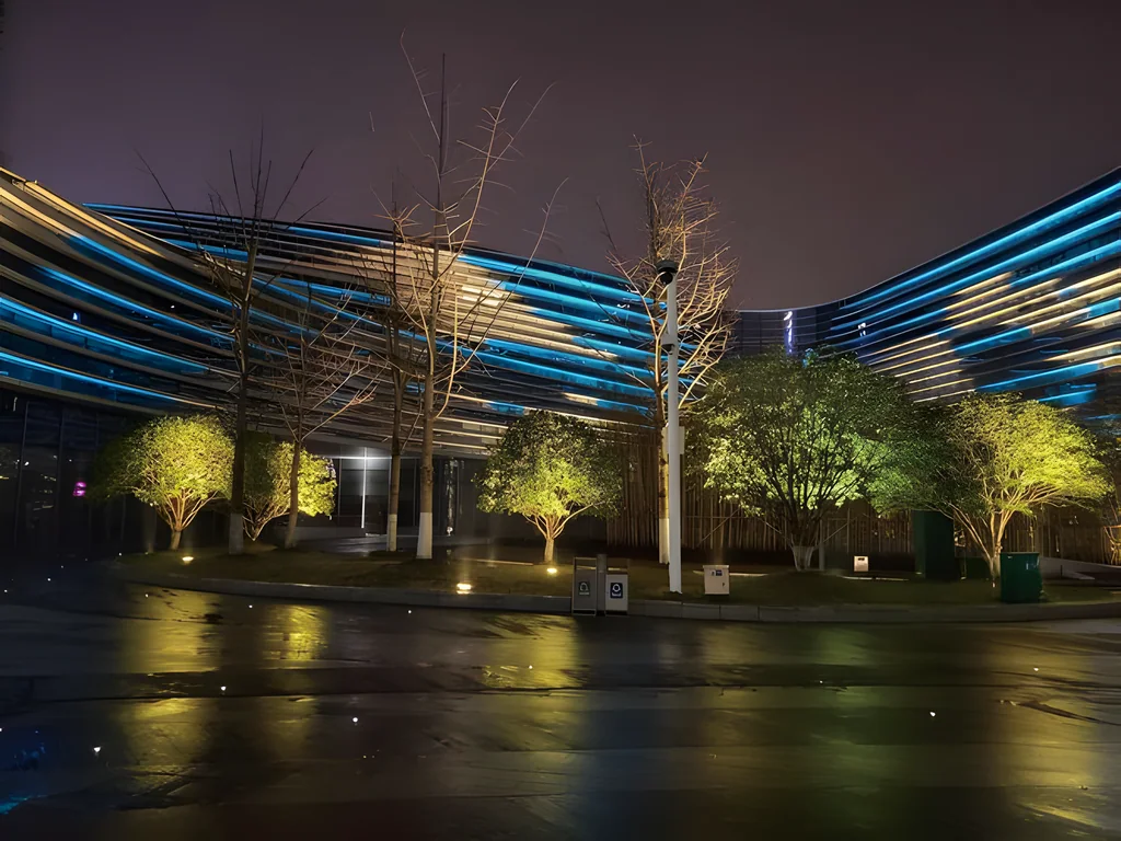 Illustrative application photo: Horizontal blue light bands on a curved façade, with uplit trees in front, at night.