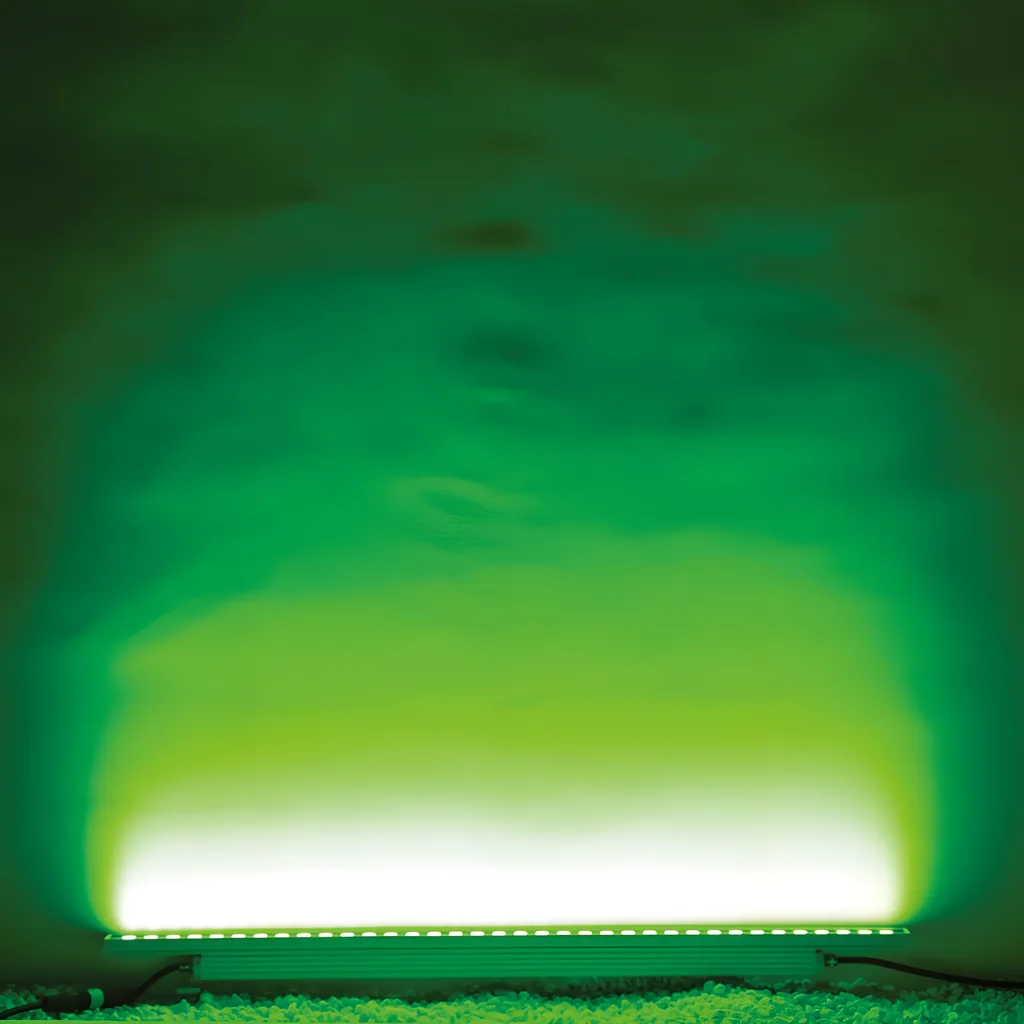 Illustrative application photo: Green wall-wash from a ground-mounted lens linear light, individual LEDs visible.