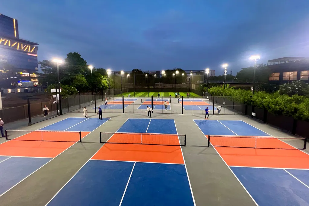 Pickleball courts under pole-mounted floodlights at dusk