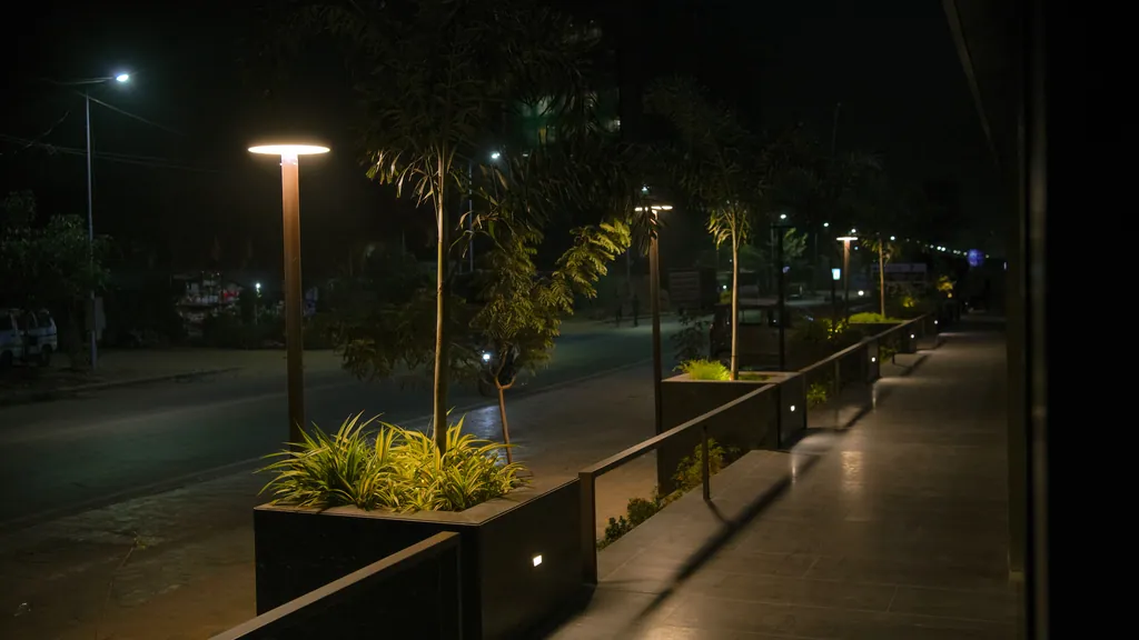 Disc post tops and planters along the walkway in front of AWS-3 Commercial Tower at night