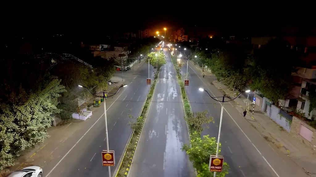 Aerial view of a divided road at night, with double-arm poles in the medians