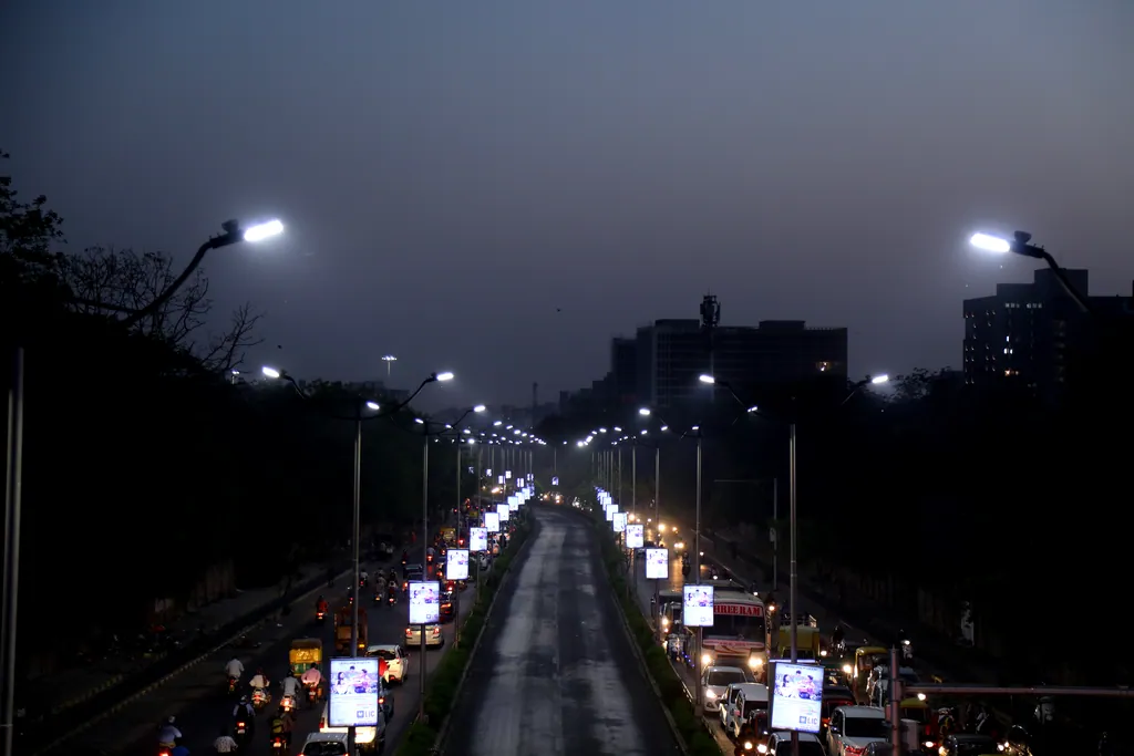 The BRTS corridor at dusk, seen from above the bus lane, with double-arm poles on both sides