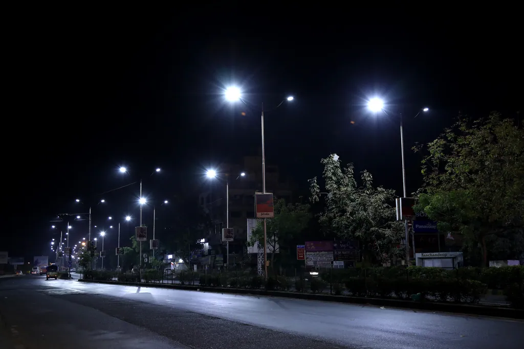 A wide divided road at night under double-arm street lights