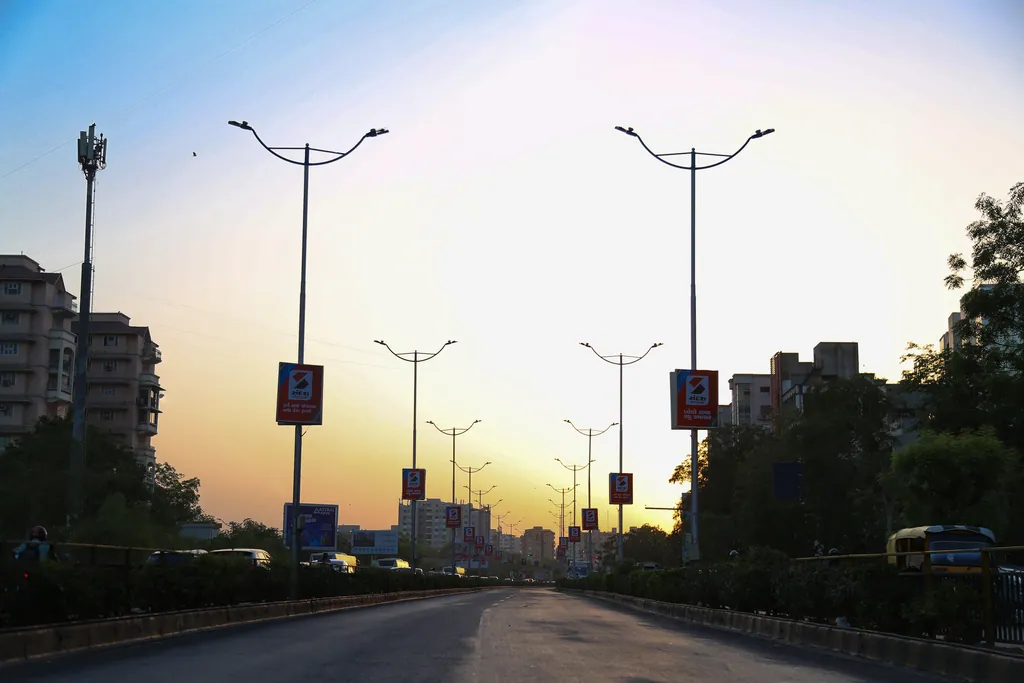 Double-arm street light poles along a road at sunset