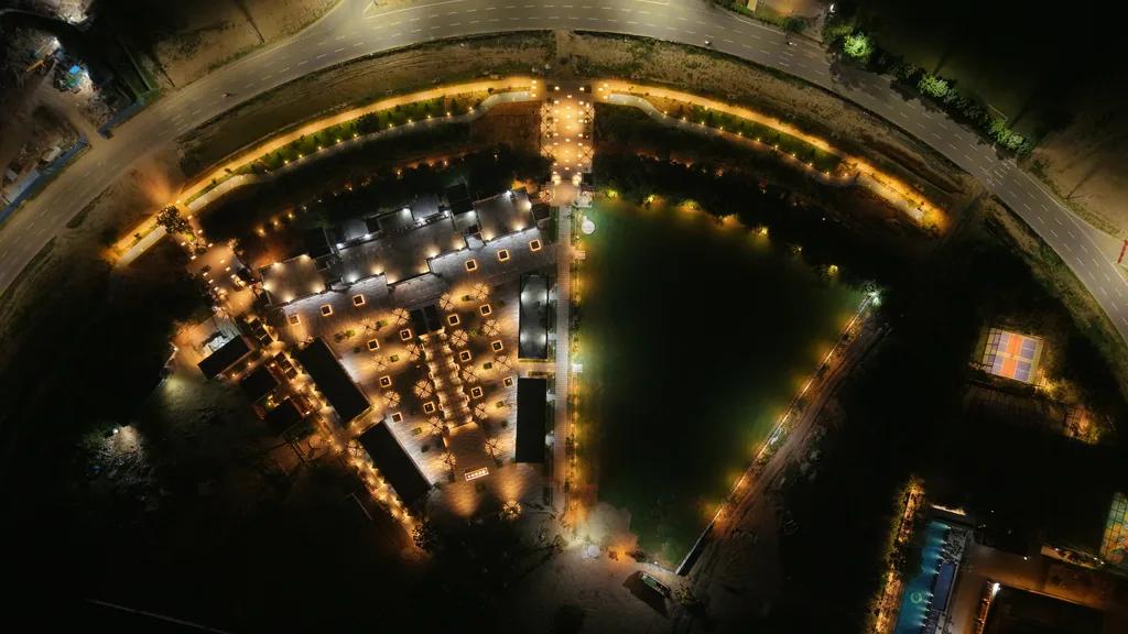 Central Park from above at night: the lit plaza, the lawn and a curved path edged with lights
