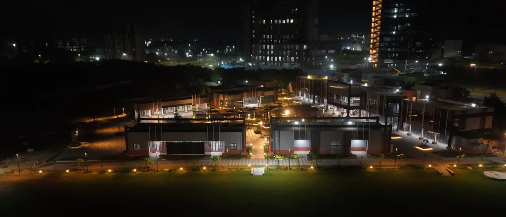 Pavilions and a line of path lights along the lawn edge at night, with towers beyond