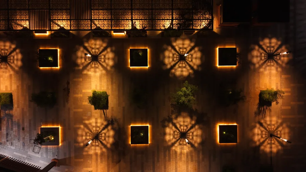Top-down view of the plaza: patterned pools of light around each pole between square planters edged in light