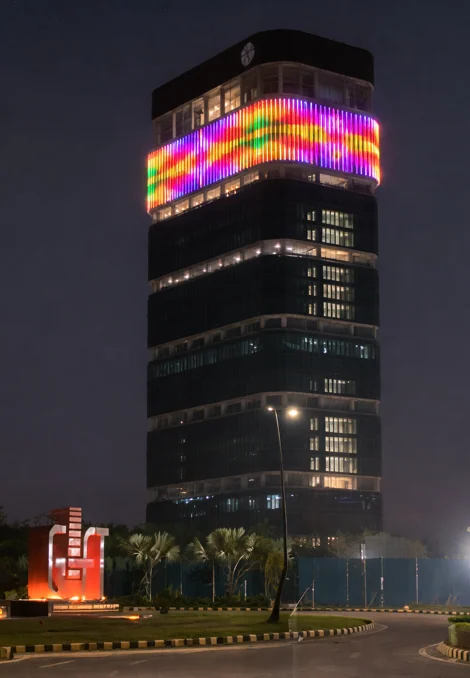 The IFSCA Building crown showing a multicolour lighting sequence at night, with the GIFT sign in the foreground