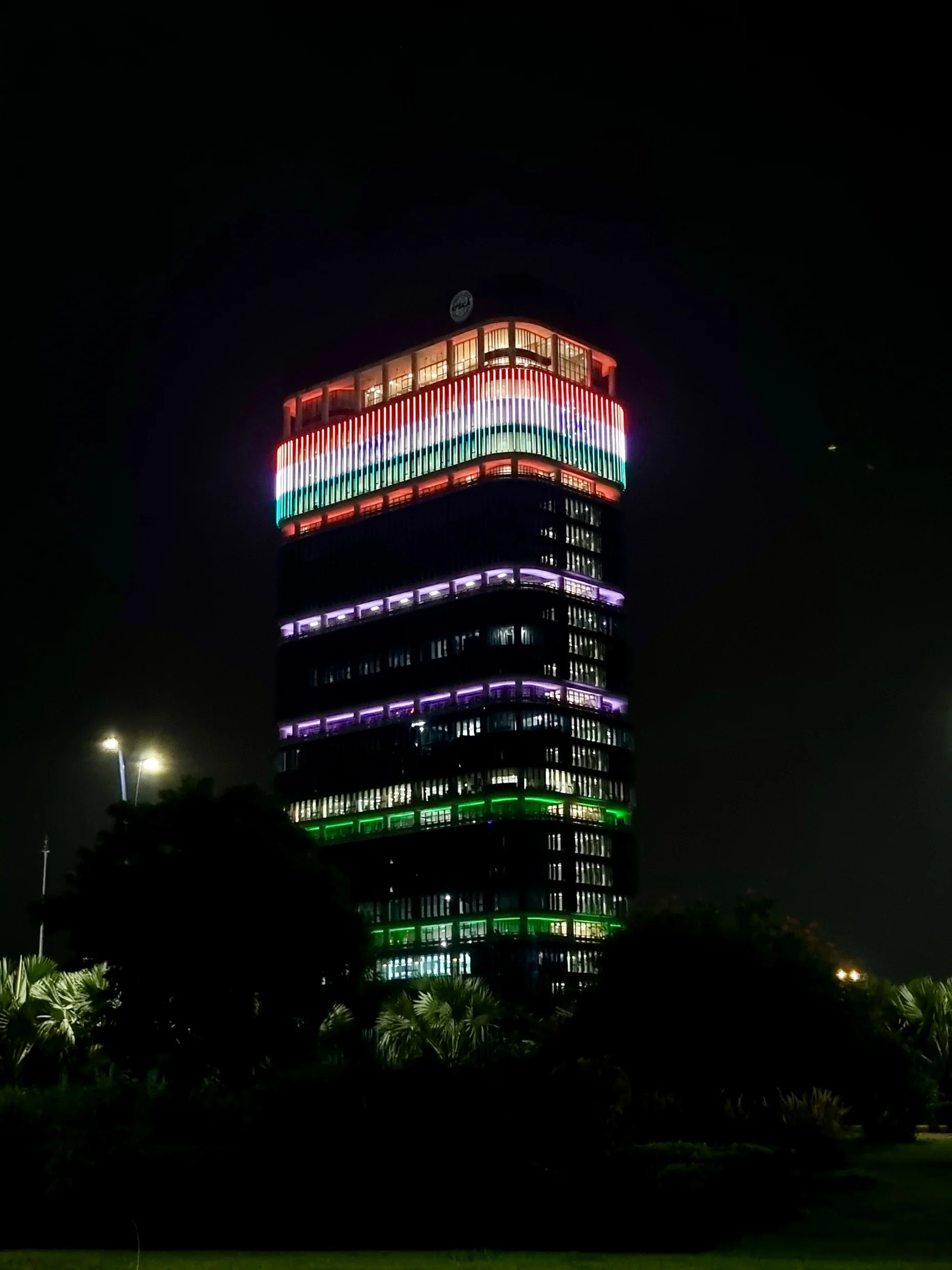 The tower at night, its crown in the colours of the national flag.