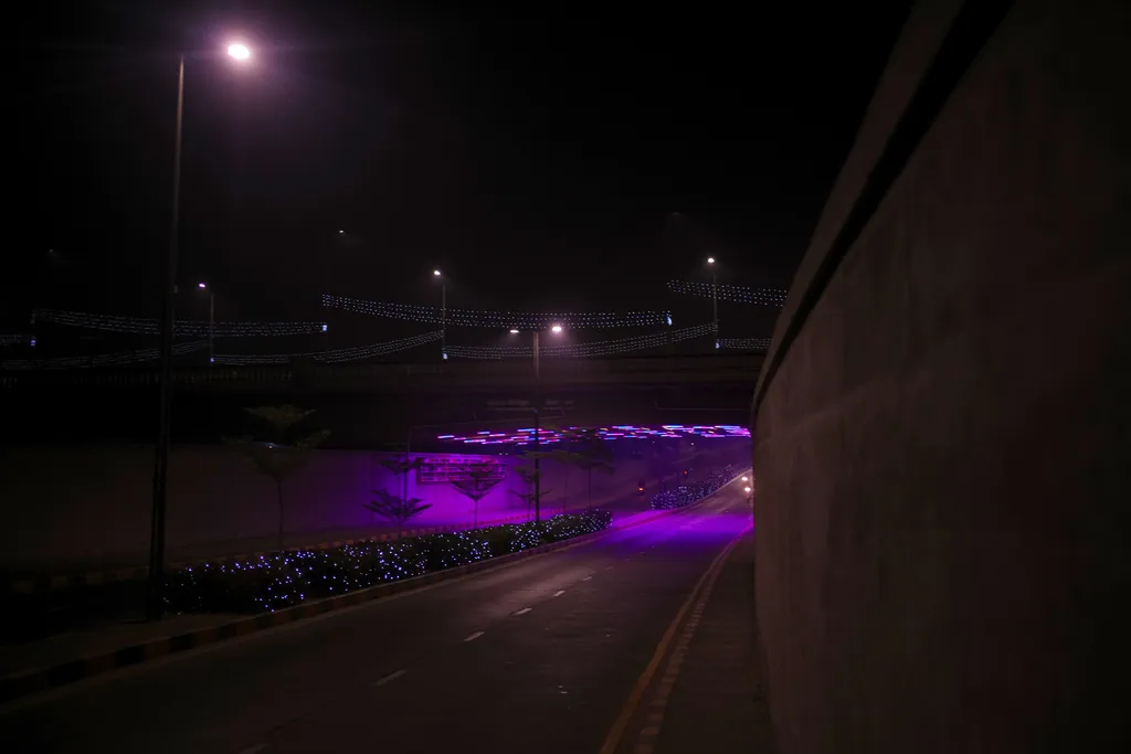 The road dipping under Nehru Bridge at night, with the lit underbridge ahead