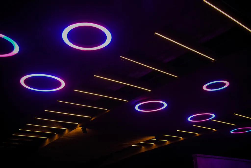 White and violet rings and warm linear lights on the concrete soffit of the bridge