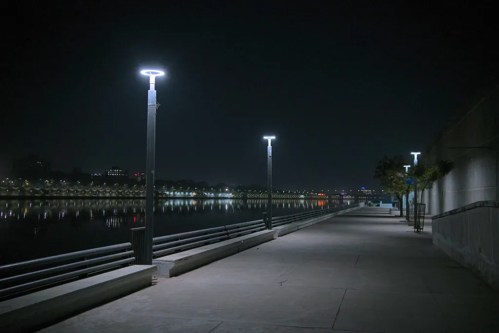 Ring post tops along the railing of the riverfront promenade at night