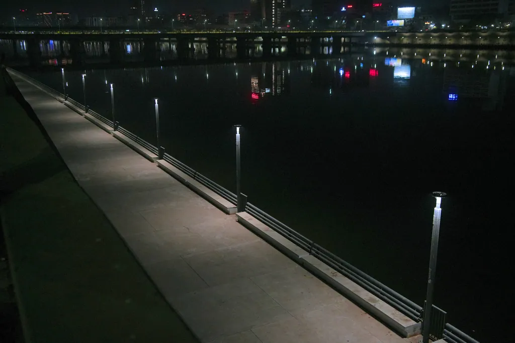 Ring post tops in a line along the promenade railing beside the river at night