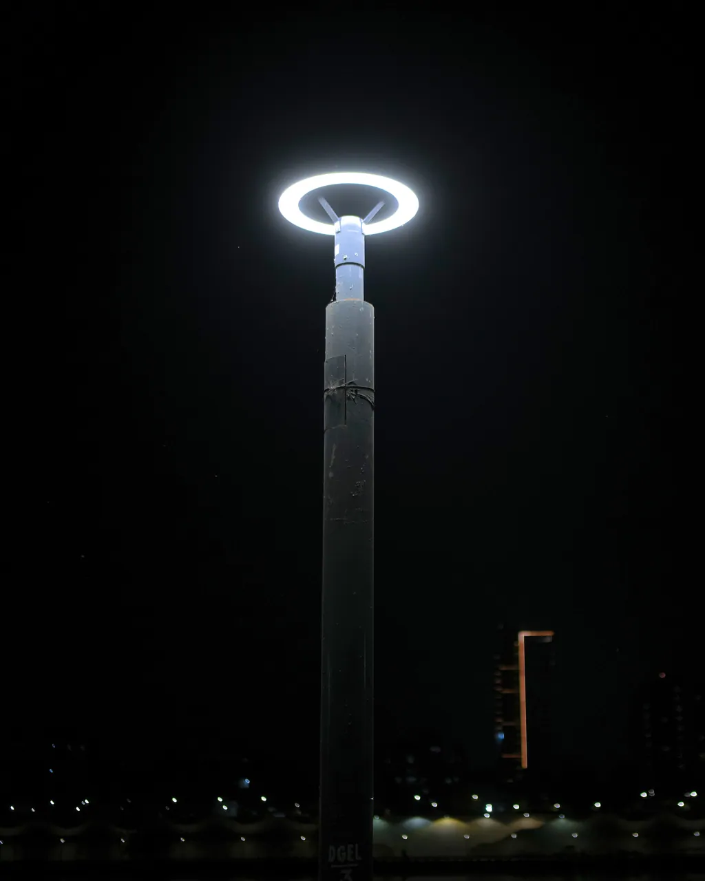 A ring post top lit against the night sky, with the far bank of the river below