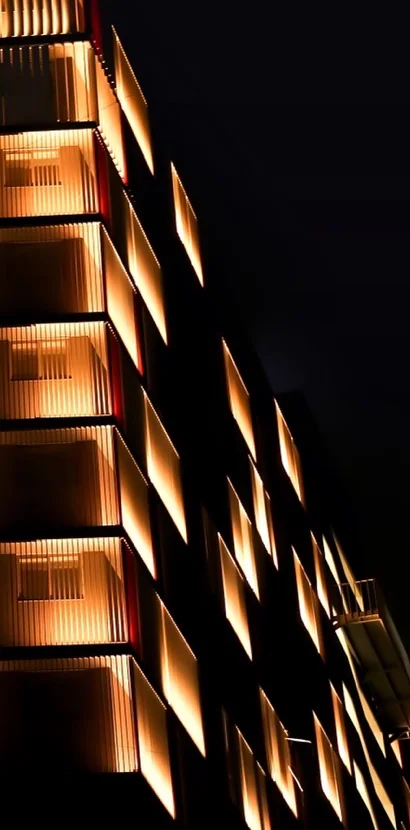 The side façade of Sakar-IX, its projecting fin bays lit at night
