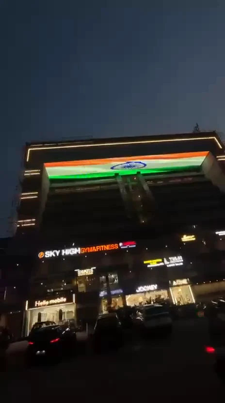 The ICONIC seen from the street at dusk, its pixel mesh band above the lit shopfronts
