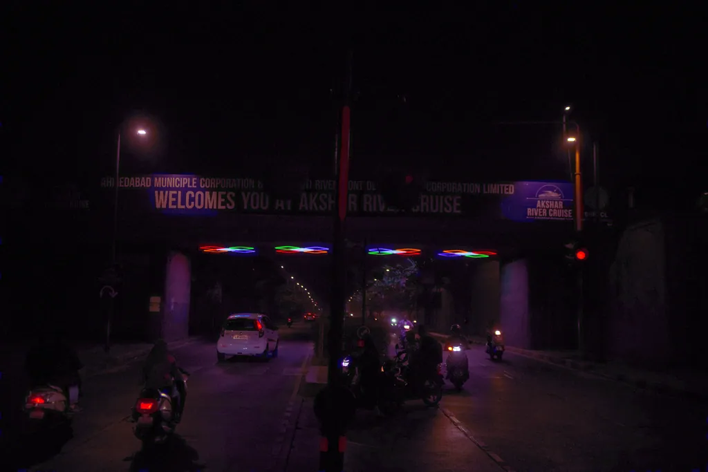 Traffic approaching the VIP Underbridge at night, with coloured clusters under the bridge and a welcome banner above