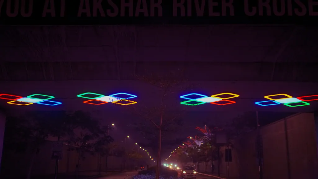 Four clusters of coloured light under the VIP Underbridge, above a tree-lined road at night