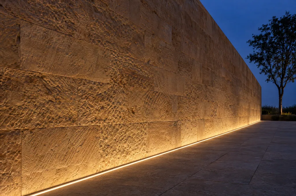 A sandstone wall grazed by a recessed linear LED at dusk